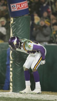 a football player standing on the sidelines with his hands in his pockets as he kneels