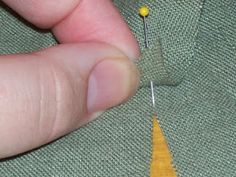 the needle is being used to sew an arrow on a green piece of cloth