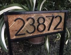 a wooden house number sign sitting in the grass