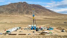 an oil rig in the middle of nowhere with mountains in the background and blue sky