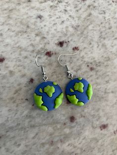 the earrings are made out of polymer and have green, blue and white designs on them