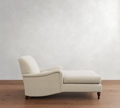 a white chaise lounge chair sitting on top of a hard wood floor next to a wall