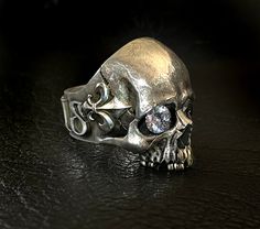 RING PROFILE: 🔱Our Mortis Fleur de Lis silver skull ring is certainly one of the most anatomically accurate and detailed skull rings on the market. We have meticulously created a statement skull ring full of character and personality. Its old and subtly sad-looking expression represents the experience and burden of a human life. 🔱To make this skull ring an even more extraordinary piece we have attached a Fleur-de-Lis on each side of the temple and the word MORTIS wrapped around the ring band t Gothic Skull Ring For Formal Occasions, Formal Gothic Skull Ring, Formal White Gold Skull Ring, Skull Rings, Exotic Jewelry, Silver Skull Ring, Tarnish Remover, Power Symbol, Animal Bones