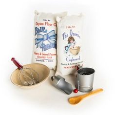 two bags of flour, a measuring cup and a whisk on a white background