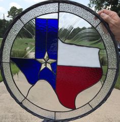 a hand holding up a stained glass window with the state of texas in red, white and blue