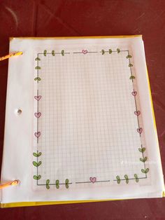 an empty notebook with flowers and hearts drawn on the paper, sitting on a table