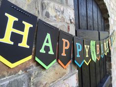 happy birthday banner hanging on the side of a brick building