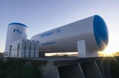 a large white and blue tank sitting on top of a cement wall next to grass