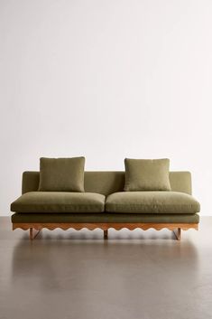 a green couch sitting on top of a hard wood floor next to a white wall