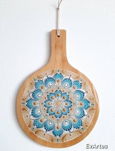 a wooden cutting board decorated with blue and white designs on it's side hanging from a wall