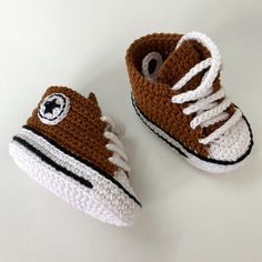 a pair of crocheted shoes with white and brown laces on the bottom