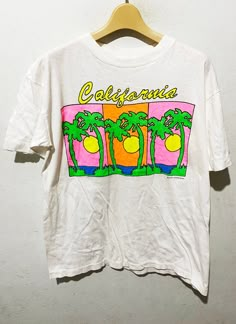 "Vintage 90s California Shirt Size: M Made In Dominican Rep Measurements are taken with the garment laying flat. Chest width: 19\" Body Length : 25\" Condition: Pre-owned 8.5/10 Material: 100% Cotton Comment Good Condition No refund. -Payment : accept paypal only -Shipping : to shipping worldwide by registered airmail (small package) Thai post registered. receiving the item within 7-30 business days non sat-sunday working after payment cleared  (some case in Australia/italy/spain/north and south america 2-4 weeks) I ship every day, monday through Friday! Many times your item will go out same day!! Get your stuff super fast when you buy from me! -Check item status out of my country: http://track.thailandpost.co.th 12 white" 90s California Aesthetic, 90s Shirts Graphic Tees, Graphic Tees Aesthetic, 90s California, Vintage Shirt Design, California Shirt, 90s Shirts, Vintage California, North And South