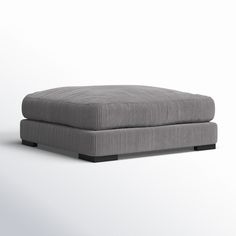 a gray ottoman sitting on top of a white floor