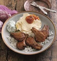 a white plate topped with meat and rice on top of a wooden table next to an onion