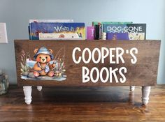 a wooden sign that says cooper's books with a teddy bear sitting on it