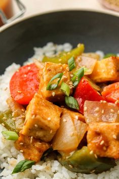 tofu and vegetables on rice in a black bowl