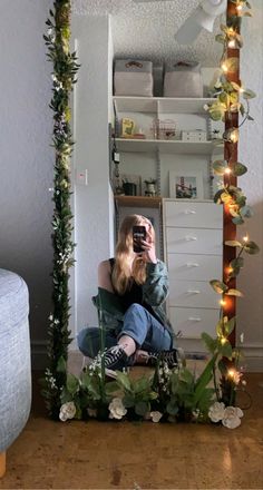 a woman taking a selfie in front of a mirror with flowers and greenery