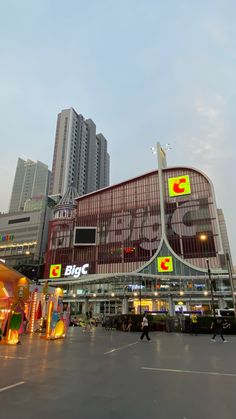 an outdoor shopping mall with people walking around it and tall buildings in the back ground