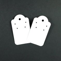 two white tags with faces on them sitting next to each other in front of a black background