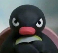 a close up of a toy penguin with big eyes and an angry look on its face