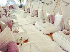 a room filled with lots of white furniture covered in pink and gold pillows on top of fluffy rugs