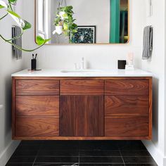 a bathroom with a sink, mirror and plant in the corner on the counter top