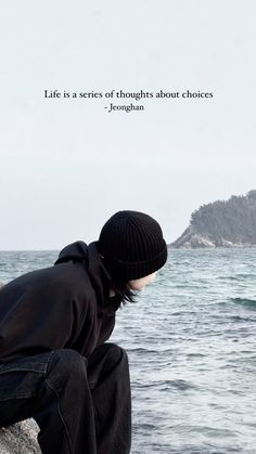 a man sitting on top of a rock next to the ocean with a quote above him