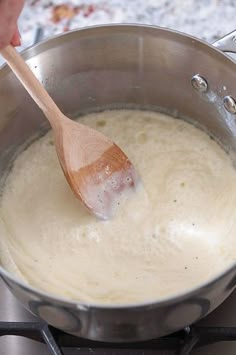 a person is stirring something in a pot on the stove top with a wooden spoon