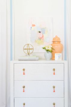 a white dresser topped with a vase filled with flowers