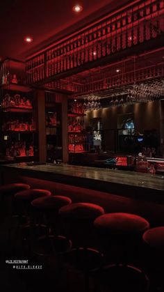 an empty bar with red lights and stools