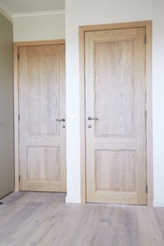 two wooden doors in an empty room with hard wood flooring and white paint on the walls