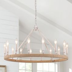 a wooden chandelier with candles hanging from it's center and two windows in the background