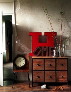 a red clock sitting on top of a wooden dresser next to a white door in a room