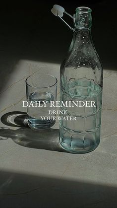 a water bottle and glass sitting on a table with the words daily reminder drink your water