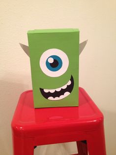 a green box sitting on top of a red stool with an evil face painted on it