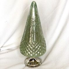 a green glass candle holder sitting on top of a white sheet