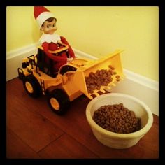 an elf is riding on a toy truck with his dog food in the bowl next to it