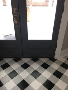 a black and white checkered floor in front of a door with two glass doors