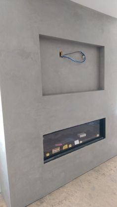 a modern fireplace in a room with concrete walls and flooring that has been painted light gray