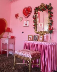 a room with pink walls and pictures on the wall, including a mirror above a bench