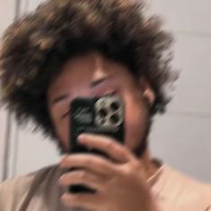 a man taking a selfie in front of a mirror with his hair blowing back