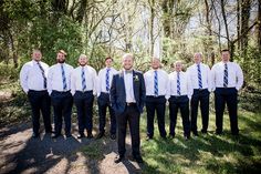 a group of men standing next to each other in front of some trees and grass