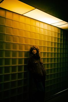 a woman standing in front of a glass block wall