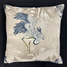 a blue and white pillow with a bird painted on it's side, in front of a black background