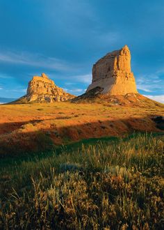 a large rock formation sitting on top of a lush green field under a blue sky