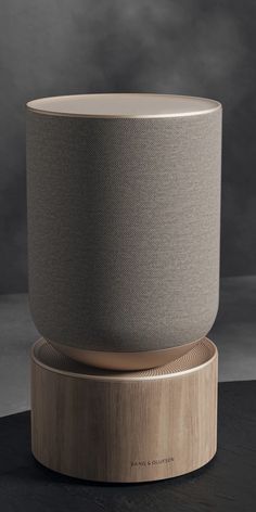 an amazon echo speaker sitting on top of a wooden stand in front of a gray background