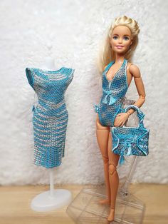 a barbie doll is posed next to a dress and purse