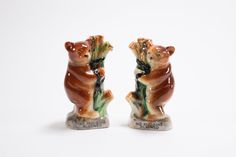 two ceramic figurines with bears holding flowers in their paws on a white background