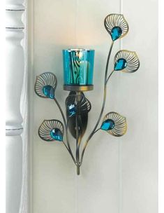 a wall light with blue glass flowers on it's side and a candle holder in the middle