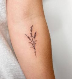 a small lavender flower tattoo on the arm